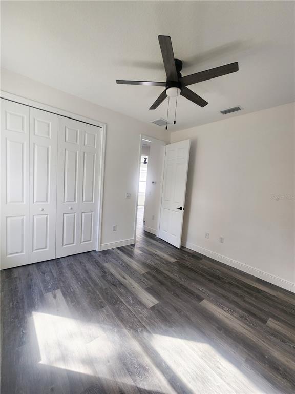9483 Southwest 121st Terrace Dunnellon, FL 34432 - Photo 27 of 42 an empty room with wooden floor fan and windows