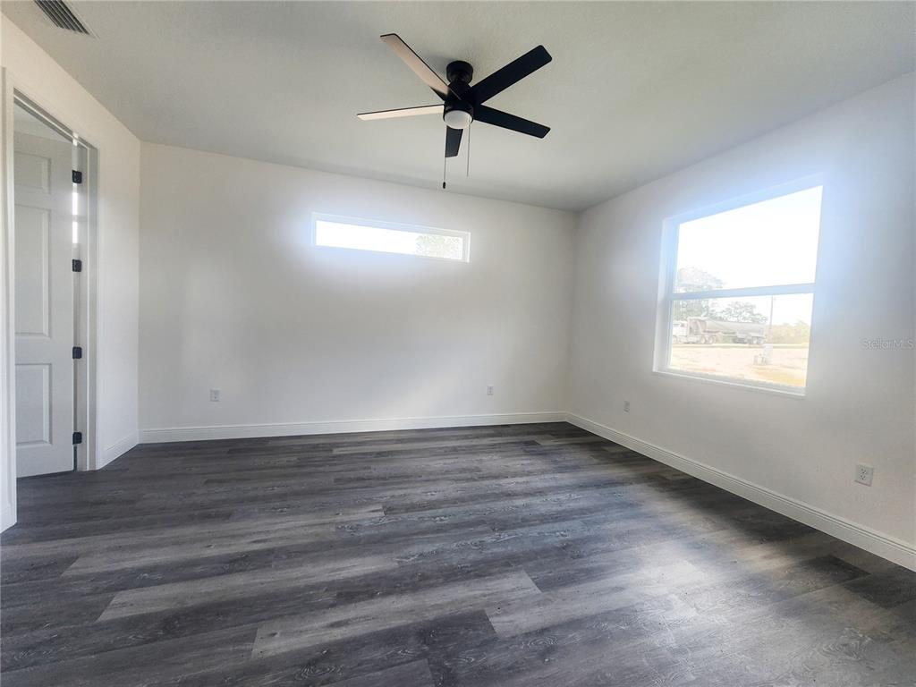 9483 Southwest 121st Terrace Dunnellon, FL 34432 - Photo 32 of 42 an empty room with wooden floor and windows