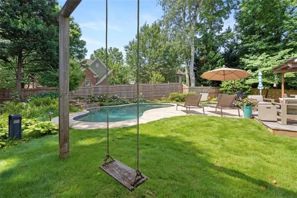 a view of a backyard with table and chairs potted plants and large tree