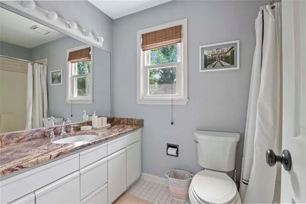 a bathroom with a granite countertop toilet sink and mirror