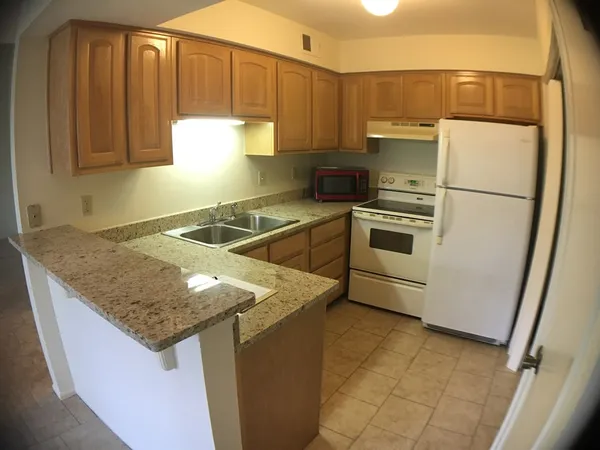 a kitchen with granite countertop a sink a stove and refrigerator