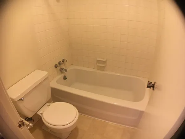 a white toilet sitting next to a bath tub