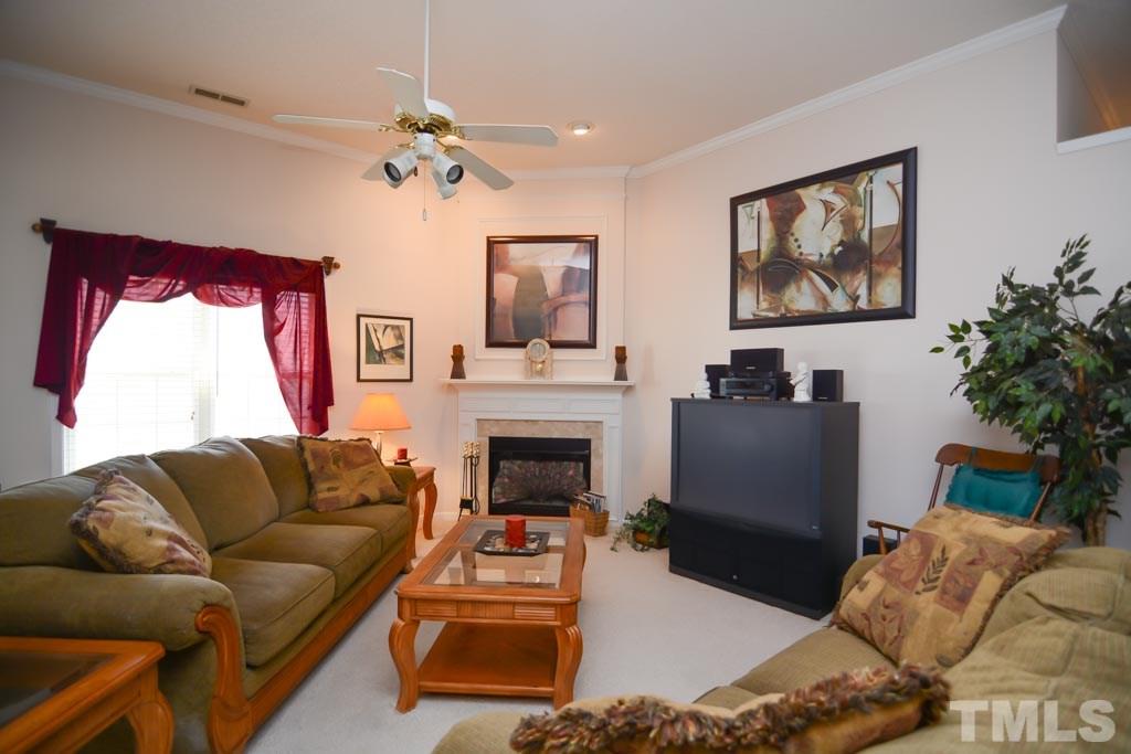 4601 Drewbridge Way Raleigh, NC 27604 - Photo 18 of 25 a living room with furniture a fireplace and a chandelier