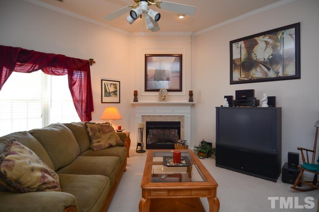 4601 Drewbridge Way Raleigh, NC 27604 - Photo 19 of 25 a living room with furniture a flat screen tv and a fireplace