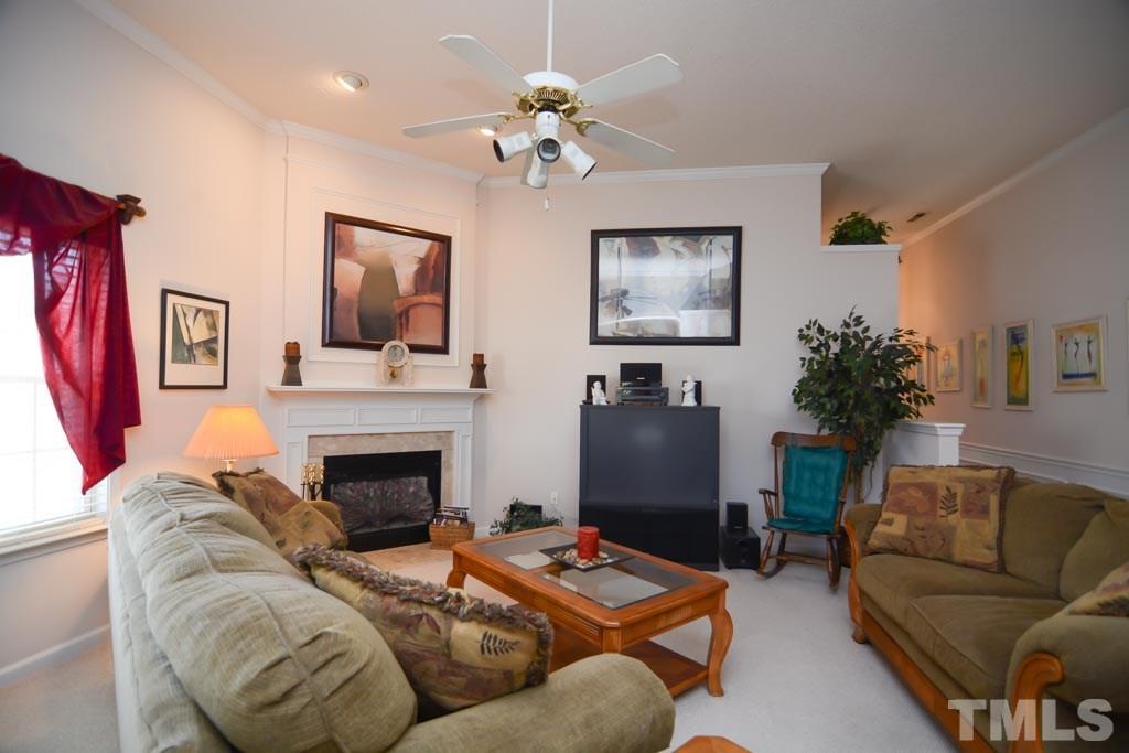 4601 Drewbridge Way Raleigh, NC 27604 - Photo 20 of 25 a living room with furniture a chandelier and a fireplace