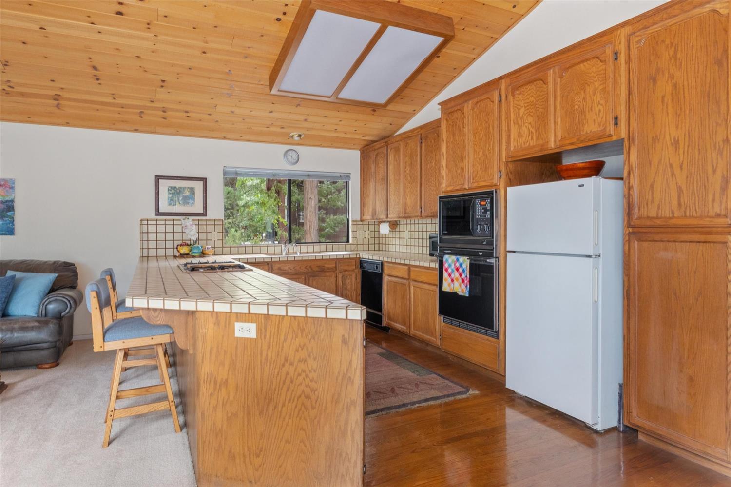 596 Sugarbush Lane Murphys, CA 95247 - Photo 13 of 48 a kitchen with a refrigerator a stove a sink dishwasher and a dining table with wooden floor