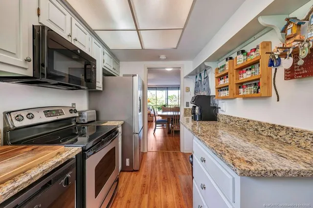 a kitchen with stainless steel appliances granite countertop a stove and a wooden floors