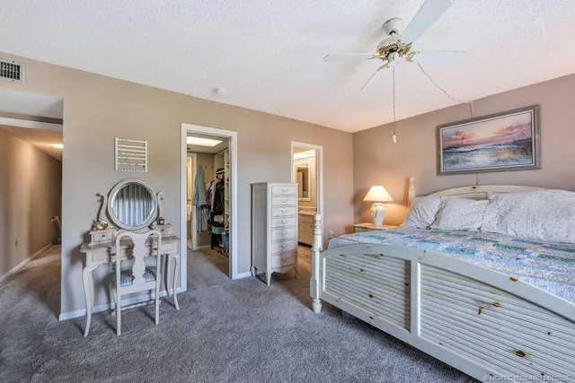 a bedroom with a bed a chandelier and a mirror on the dresser