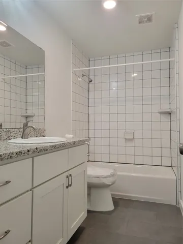 a bathroom with a granite countertop sink a toilet and shower