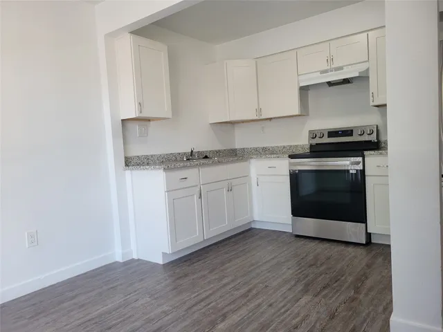 a kitchen with stainless steel appliances granite countertop a stove a sink and white cabinets