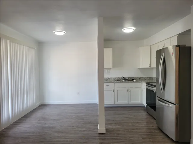 a kitchen with a refrigerator stove and wooden floor