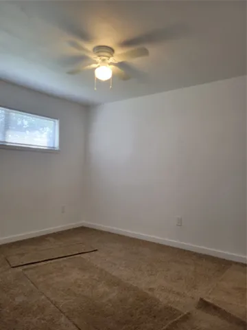 a view of an empty room with a chandelier fan