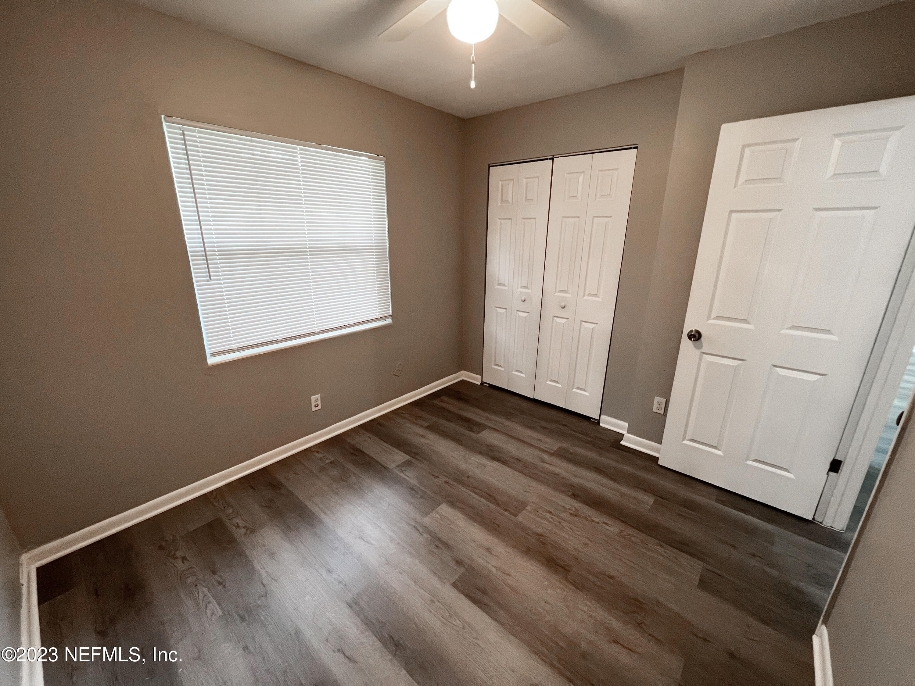 4719 Andromeda Road Jacksonville, FL 32210 - Photo 17 of 28 an empty room with wooden floor cabinet and windows