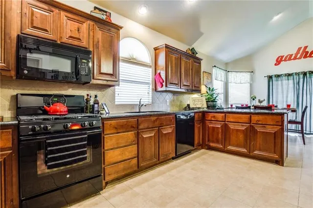 a kitchen with stainless steel appliances granite countertop a stove top oven a sink dishwasher and a microwave oven on the blue kitchen countertops