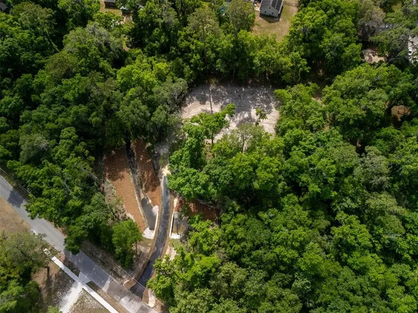 an aerial view of residential house with outdoor space and trees all around