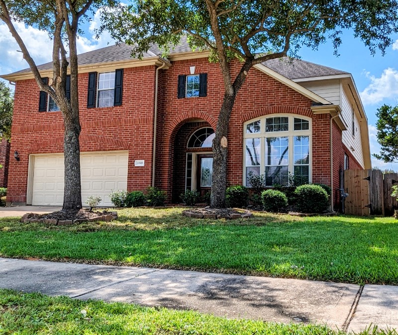 20909 Springport Court Katy, TX 77450 - Photo 2 of 39 Stunning two-story brick home with elegant arched windows, a spacious two-car garage, and lush landscaping framed by mature trees.