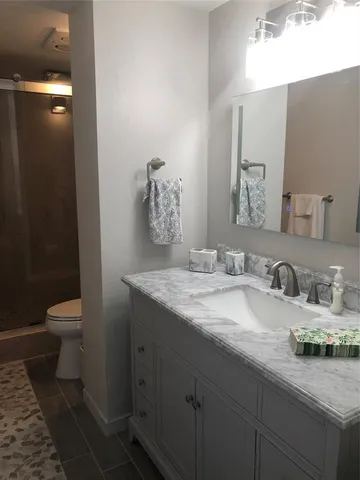 a bathroom with a granite countertop sink a toilet and a mirror