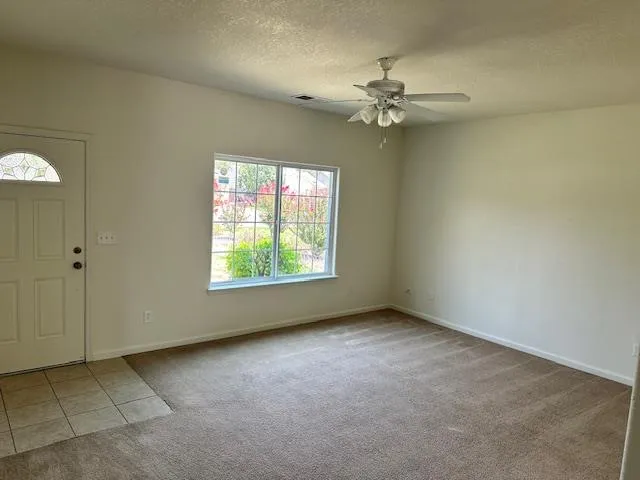 an empty room with windows and fan