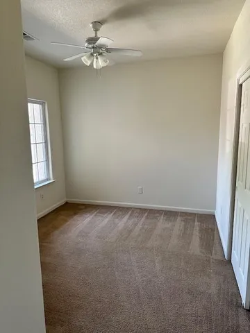 an empty room with windows and fan