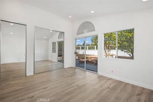 an empty room with wooden floor and windows
