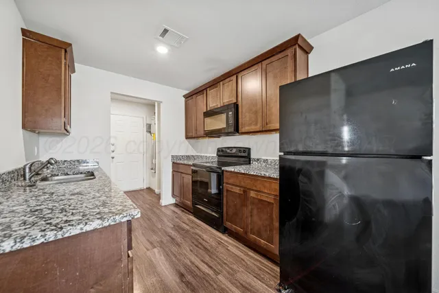 a kitchen with stainless steel appliances granite countertop a refrigerator a stove and a sink