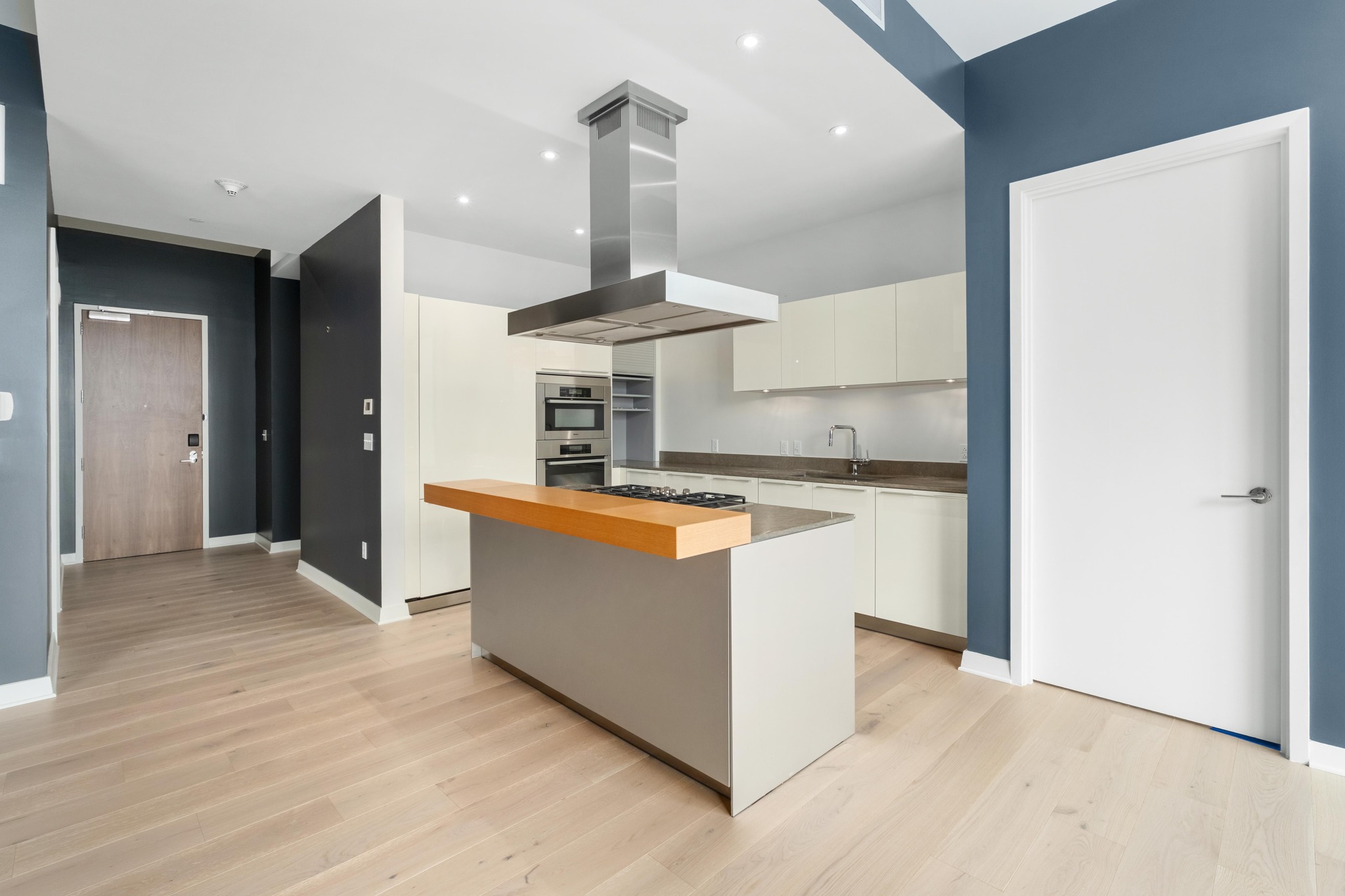 210 Lavaca Street, Unit 1810 Austin, TX 78701 - Photo 5 of 28 Kitchen with island range hood, a kitchen island, light wood-style flooring, wooden counters, and white cabinets