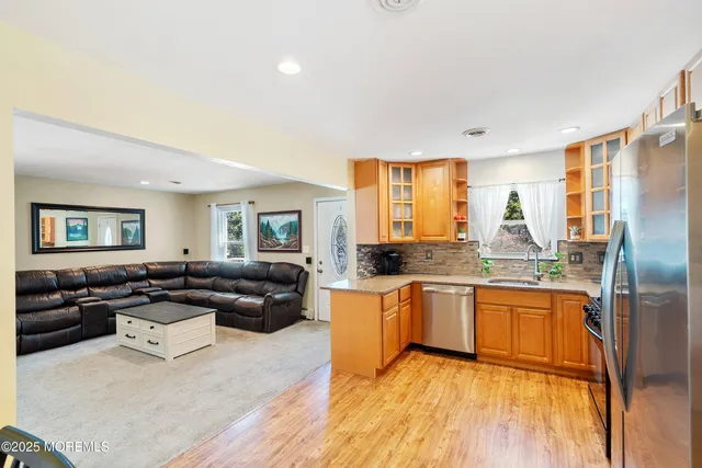 a living room with stainless steel appliances granite countertop furniture a refrigerator a sink and a stove