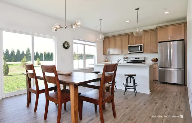 a kitchen with stainless steel appliances a dining table chairs microwave and sink