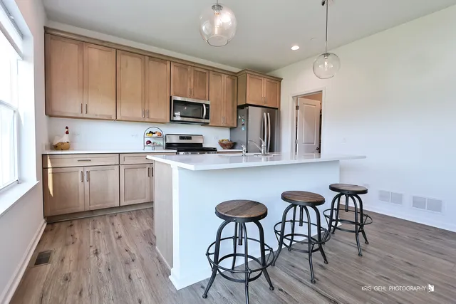 a kitchen with stainless steel appliances granite countertop a refrigerator stove and sink with wooden cabinets