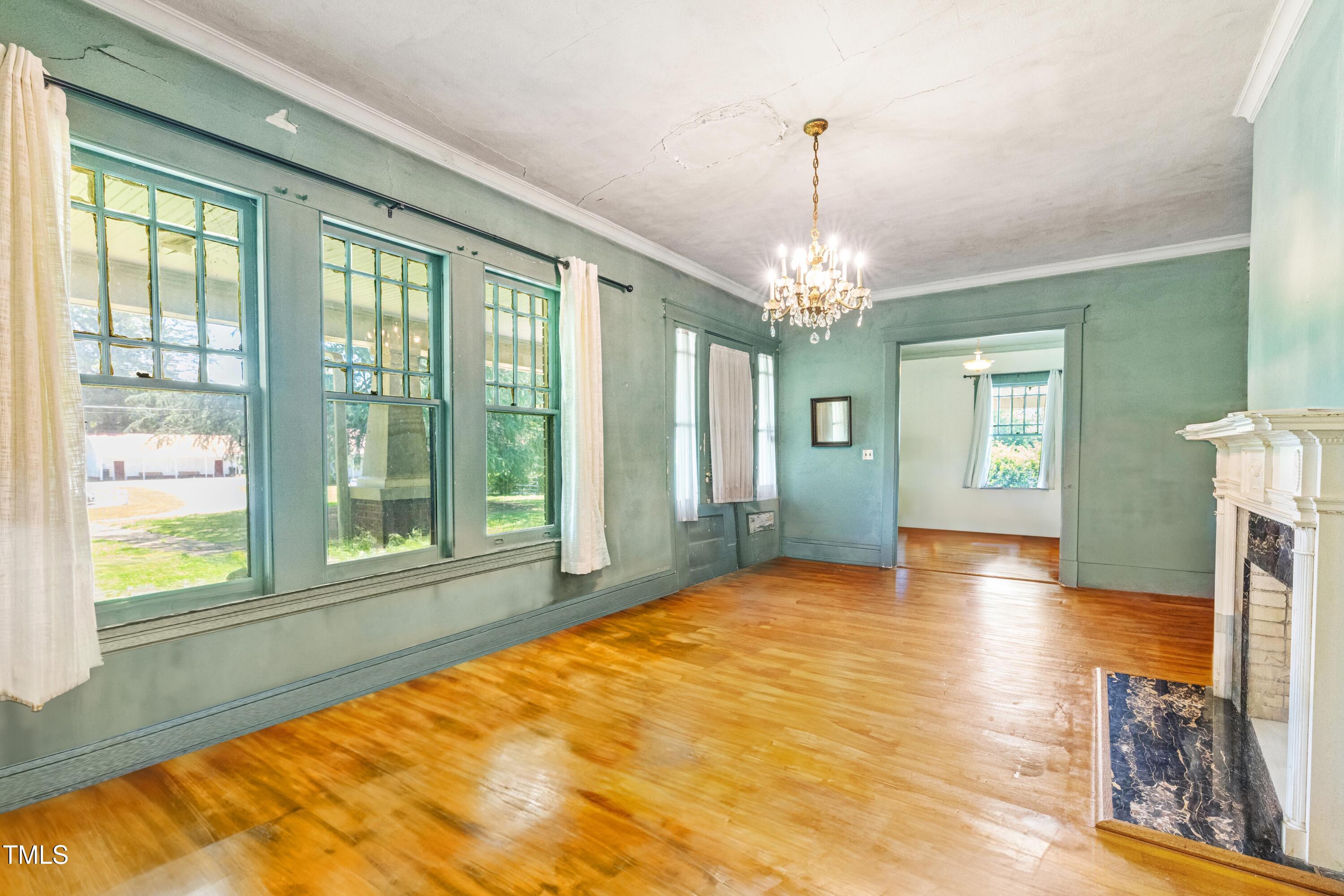 7090 Peele Road Bailey, NC 27807 - Photo 7 of 22 Photo edited to remove furniture and personal items. Living room with original crystal chandelier and fireplace. Looking out on to the wrap around porch