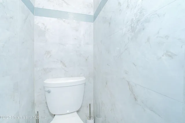 a white toilet sitting next to a white wall
