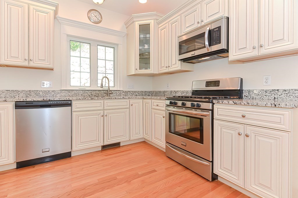 82 Swift Road Framingham, MA 01702 - Photo 2 of 39 a kitchen with stainless steel appliances granite countertop white cabinets a sink a stove a microwave and cabinetry