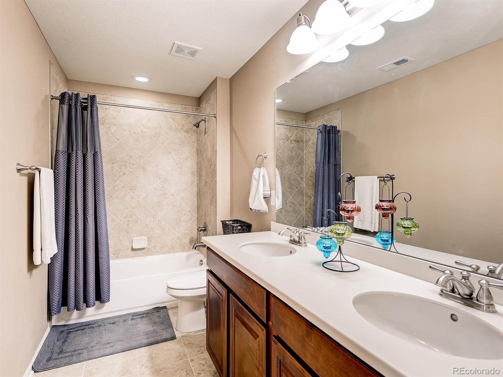 714 Springvale Road Castle Rock, CO 80104 - Photo 20 of 28 a bathroom with a granite countertop sink a toilet a mirror and shower
