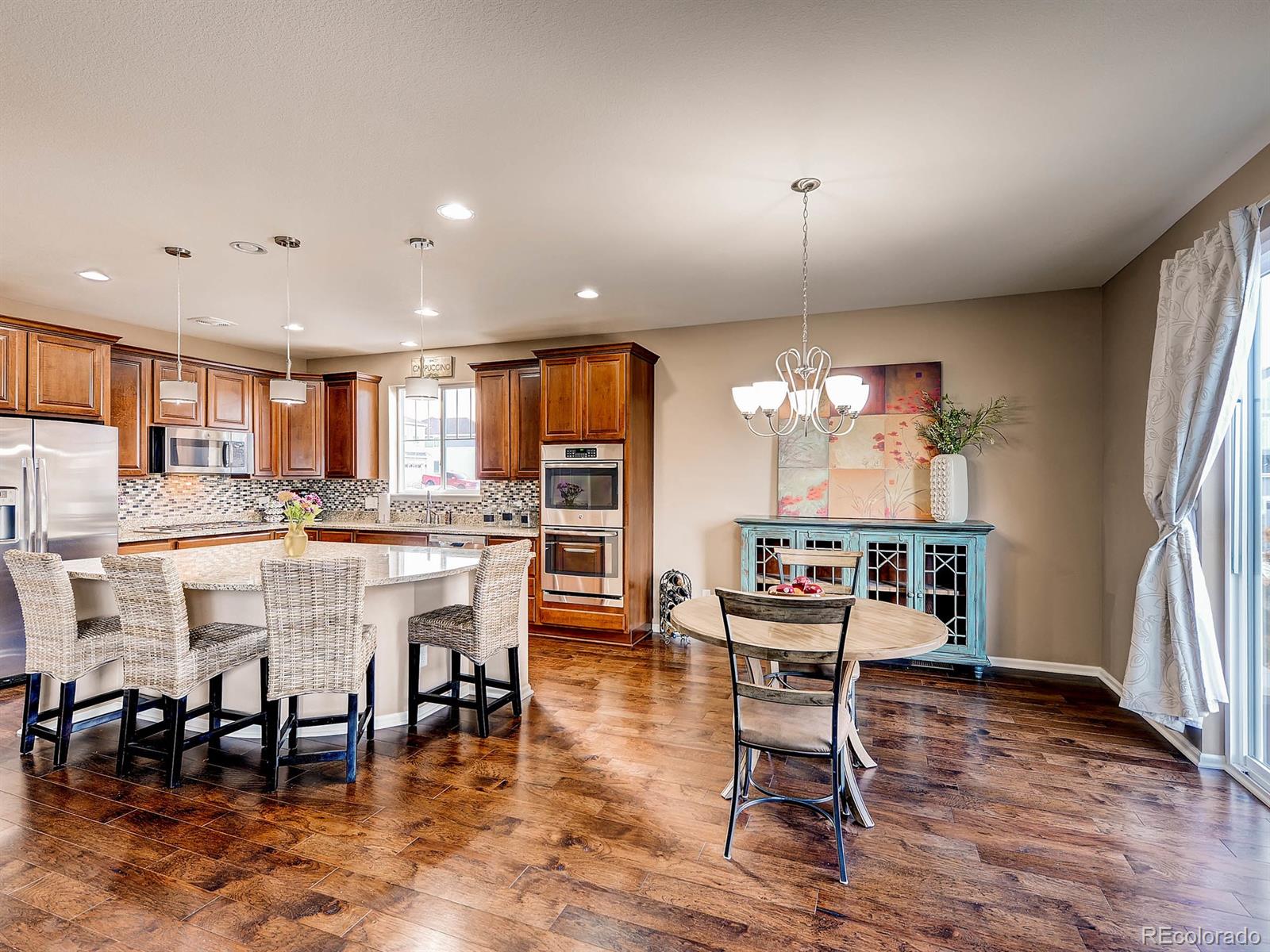 714 Springvale Road Castle Rock, CO 80104 - Photo 9 of 28 a dining room with stainless steel appliances kitchen island granite countertop a table chairs and a refrigerator