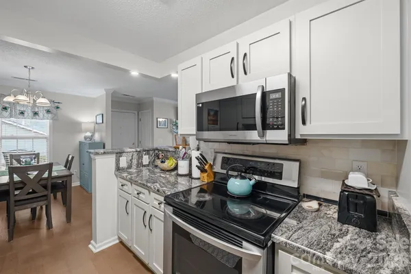 a kitchen with stainless steel appliances granite countertop a stove a sink and a microwave