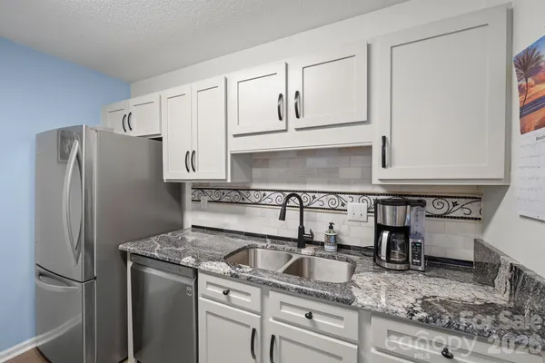 a kitchen with granite countertop a refrigerator sink stove and cabinets
