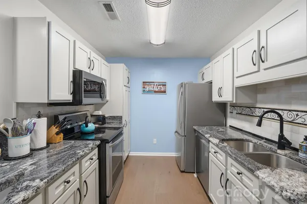 a kitchen with stainless steel appliances granite countertop a sink stove and refrigerator