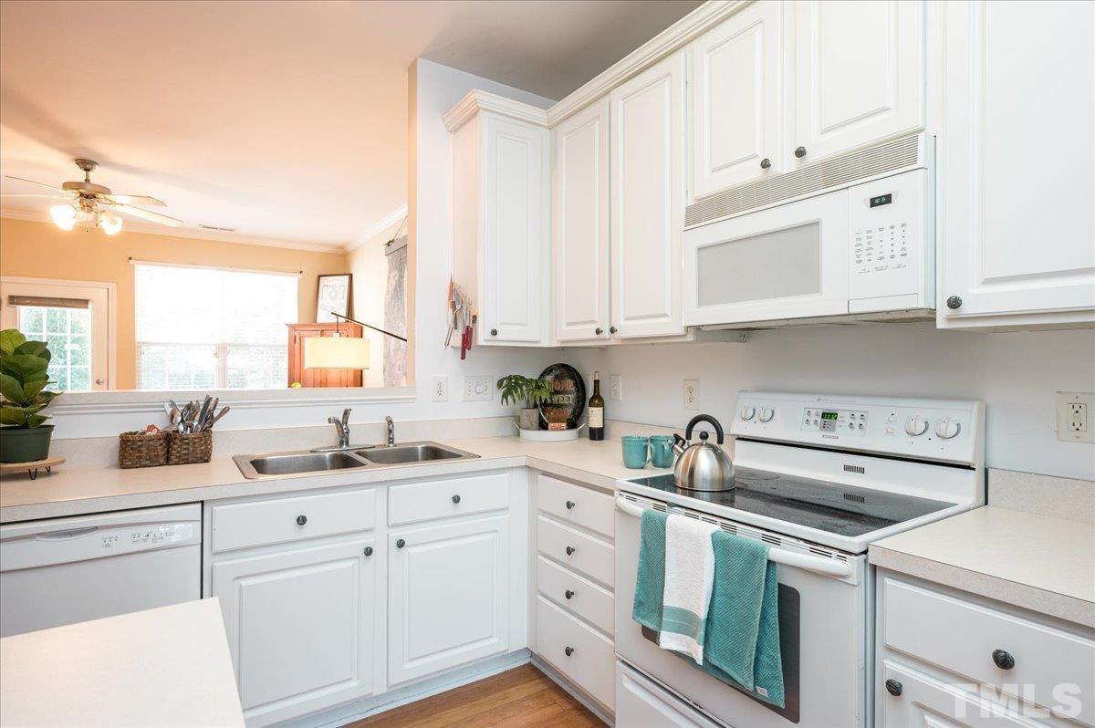 8342 City Loft Court Raleigh, NC 27613 - Photo 8 of 23 a kitchen with white cabinets and white appliances