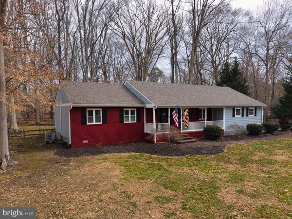 a front view of a house with yard and large tree