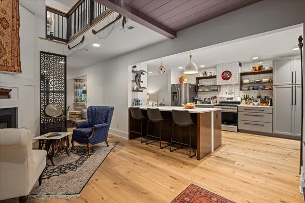 a very nice looking living room with stainless steel appliances granite countertop furniture a rug and a window