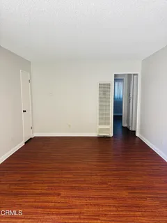 a view of an empty room with wooden floor and closet