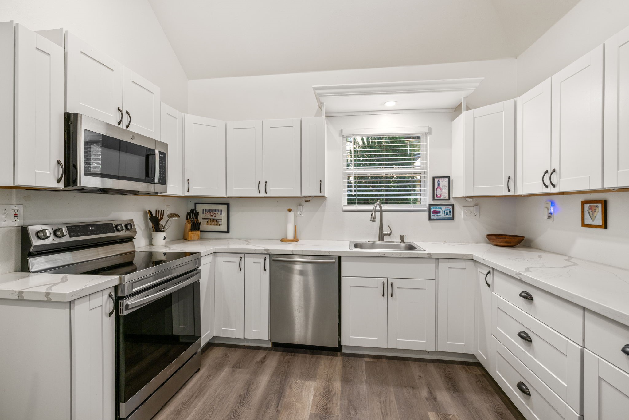 3018 McDonald Lane Spring, TX 77380 - Photo 34 of 48 a kitchen with stainless steel appliances granite countertop white cabinets a sink a stove a microwave and wooden floors