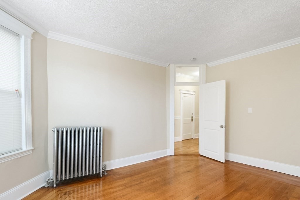 71 Walnut Park Boston, MA 02119 - Photo 20 of 36 an empty room with wooden floor and windows