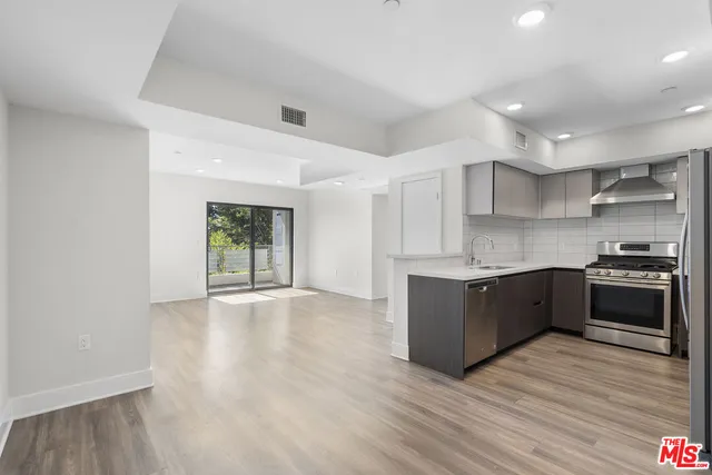 a large kitchen with wooden floors and stainless steel appliances