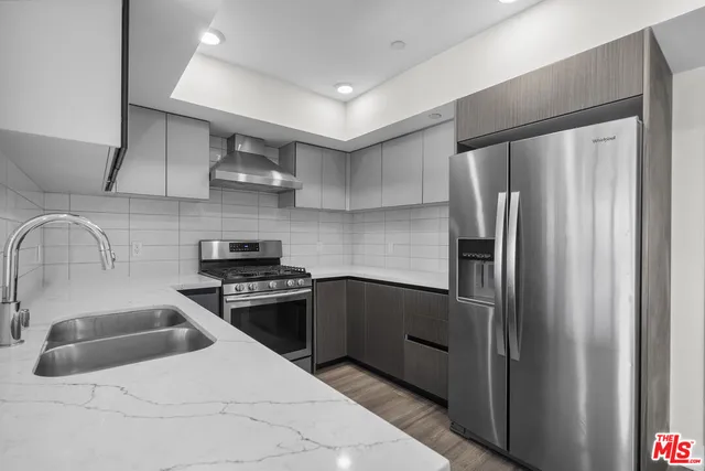 a kitchen with stainless steel appliances granite countertop a refrigerator a sink and a stove