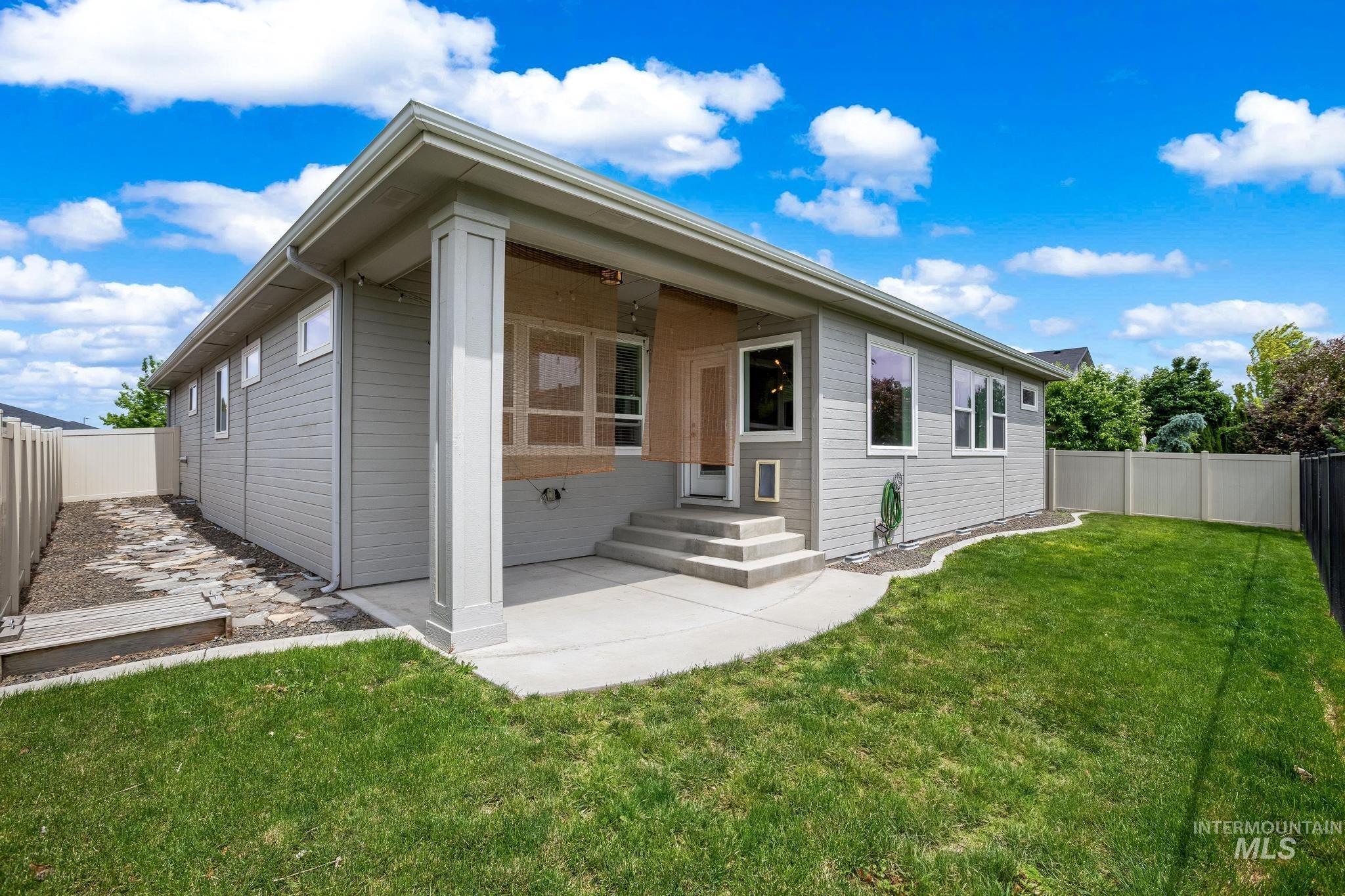 2681 East Rhyolite Court Nampa, ID 83686 - Photo 39 of 48 Exterior features include light gray siding, a covered patio with concrete steps, and a fully fenced backyard with a lawn