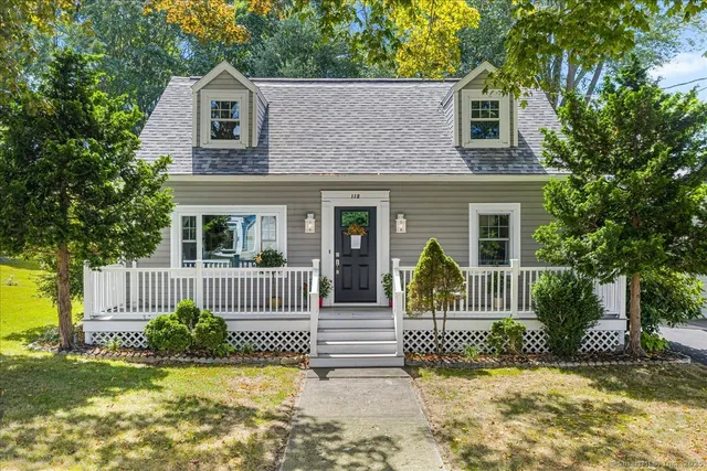 a view of a house with a small yard plants and a large tree