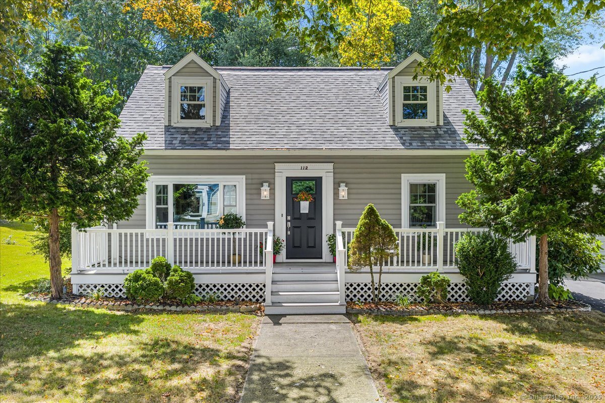 a view of a house with a small yard plants and a large tree
