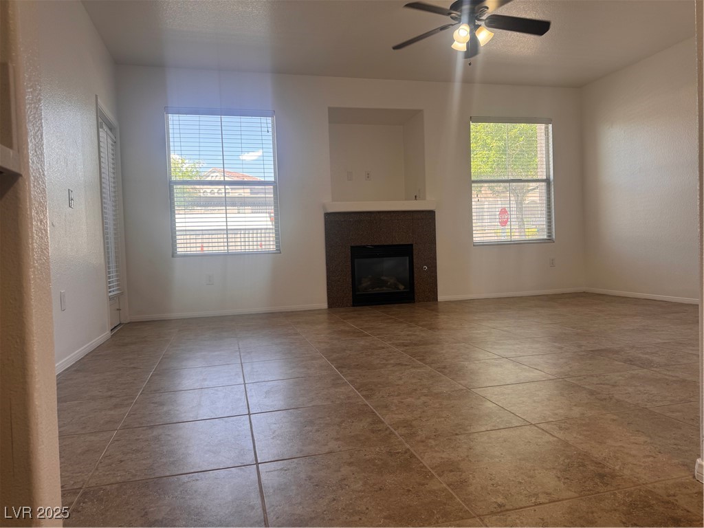 9975 Peace Way, Unit 1140 Las Vegas, NV 89147 - Photo 2 of 23 Unfurnished living room with a tile fireplace, baseboards, tile patterned flooring, and ceiling fan