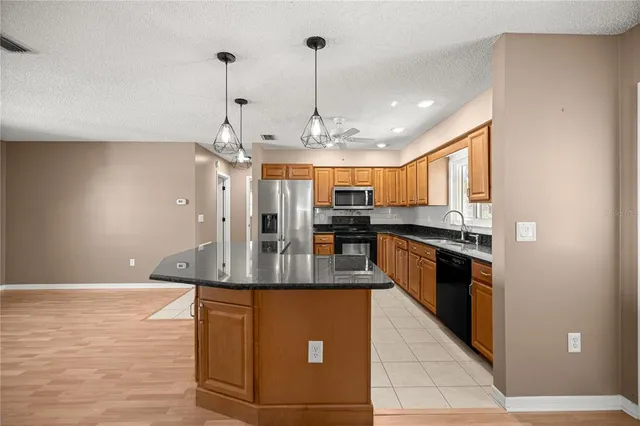 a kitchen with stainless steel appliances granite countertop a refrigerator a sink a stove a microwave and cabinets